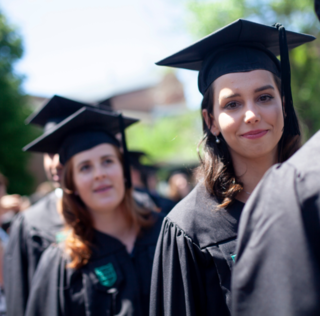 two women in graduation caps and gowns in a line of people